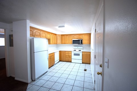 A kitchen with white appliances and wooden cabinets.