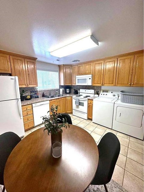 A kitchen with a table and chairs in the middle.