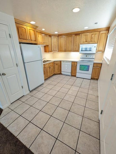 A kitchen with white appliances and wooden cabinets.