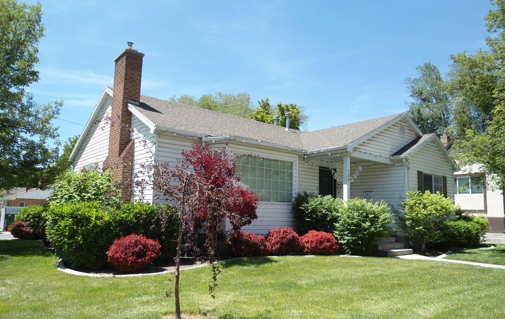 A house with a grey roof and a red tree in front.