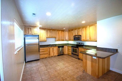 A kitchen with wooden cabinets and a black countertop.
