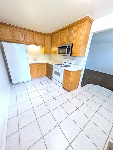 A kitchen with wooden cabinets and white appliances.
