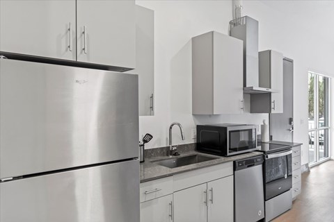 A modern kitchen with stainless steel appliances and white cabinets. at Paperbox Lofts, Salt Lake City