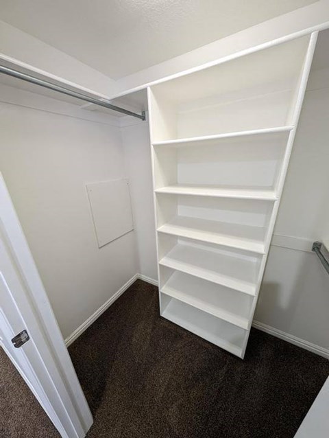 A white shelving unit in a room with white walls.
