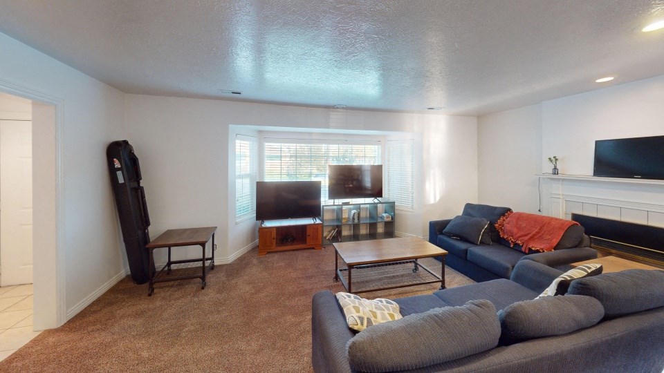 A living room with a grey couch and a fireplace.