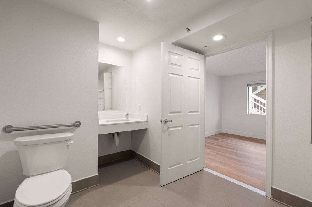 A white toilet is in a small bathroom with a white door at AVIA Lofts on Parkway Apartments, Washington, 98662