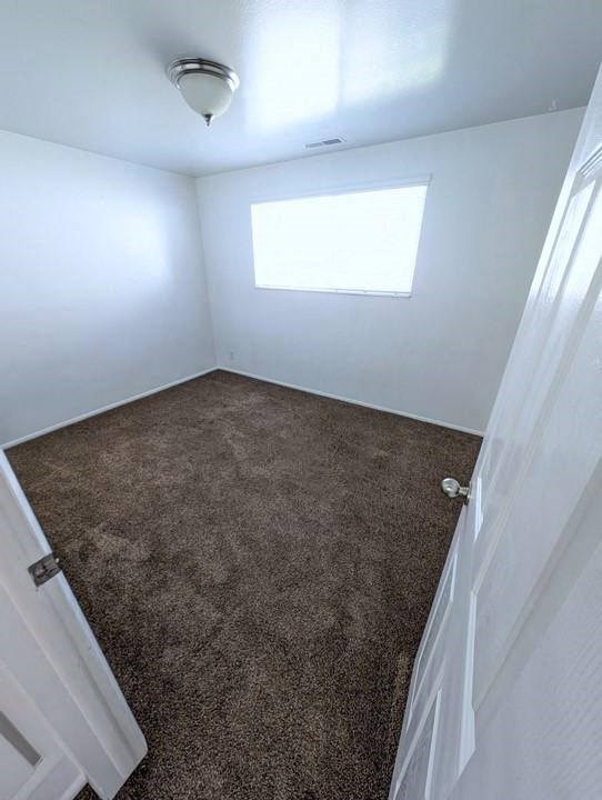 A room with a carpeted floor and a window.
