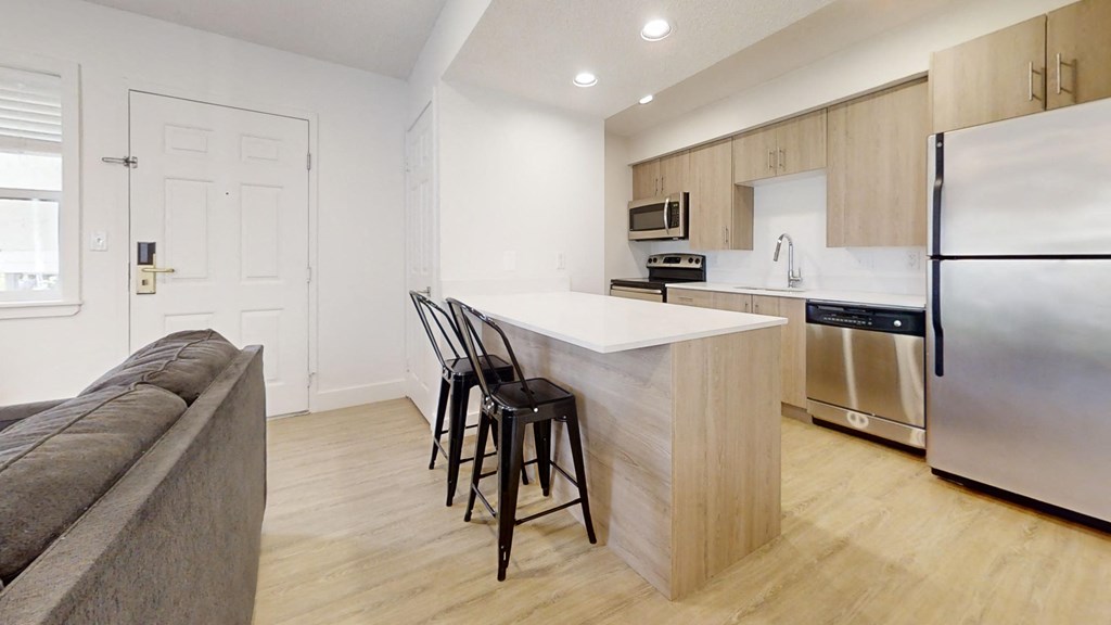 a kitchen with a white counter top and a stainless steel refrigerator