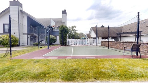 a tennis court in the backyard of a house with a bench