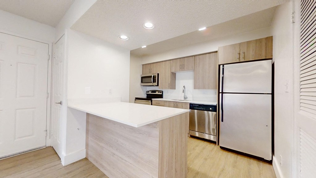 a kitchen with a white counter top and a stainless steel refrigerator