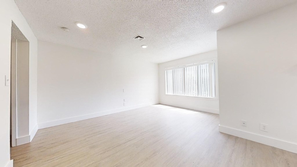 an empty living room and dining room with white walls and wood floors