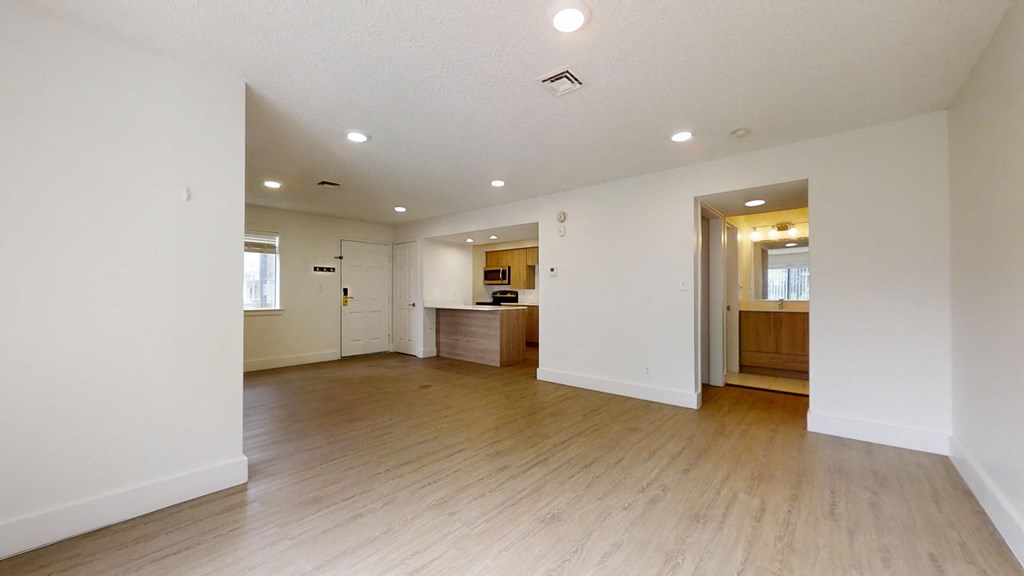 an empty living room and kitchen with white walls and wood floors