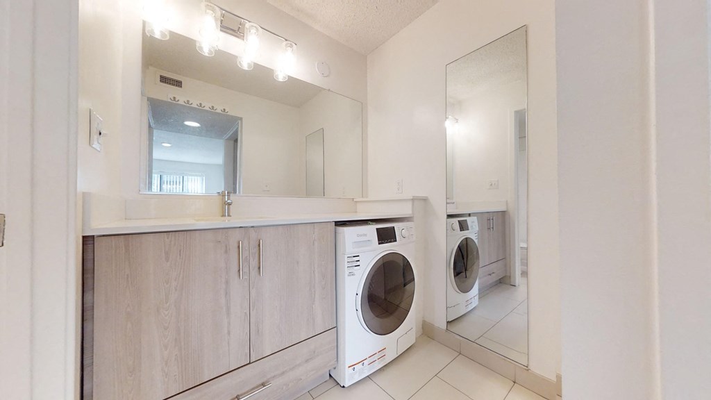 a washer and dryer in a laundry room with a sink and a mirror
