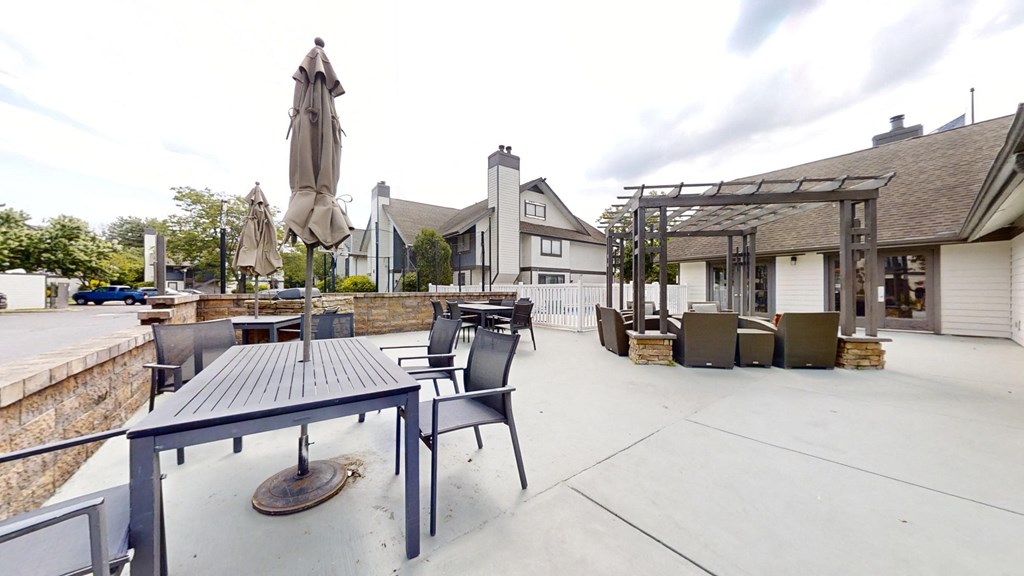 the patio at the clubhouse has tables and chairs and umbrellas