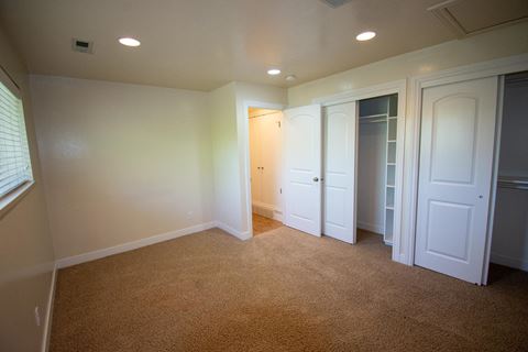 a bedroom with a carpeted floor and white closets