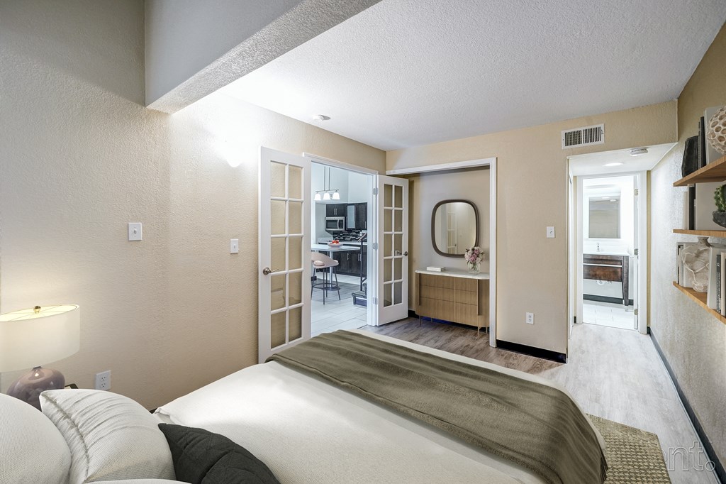 A bedroom with a bed, a desk, and a mirror.