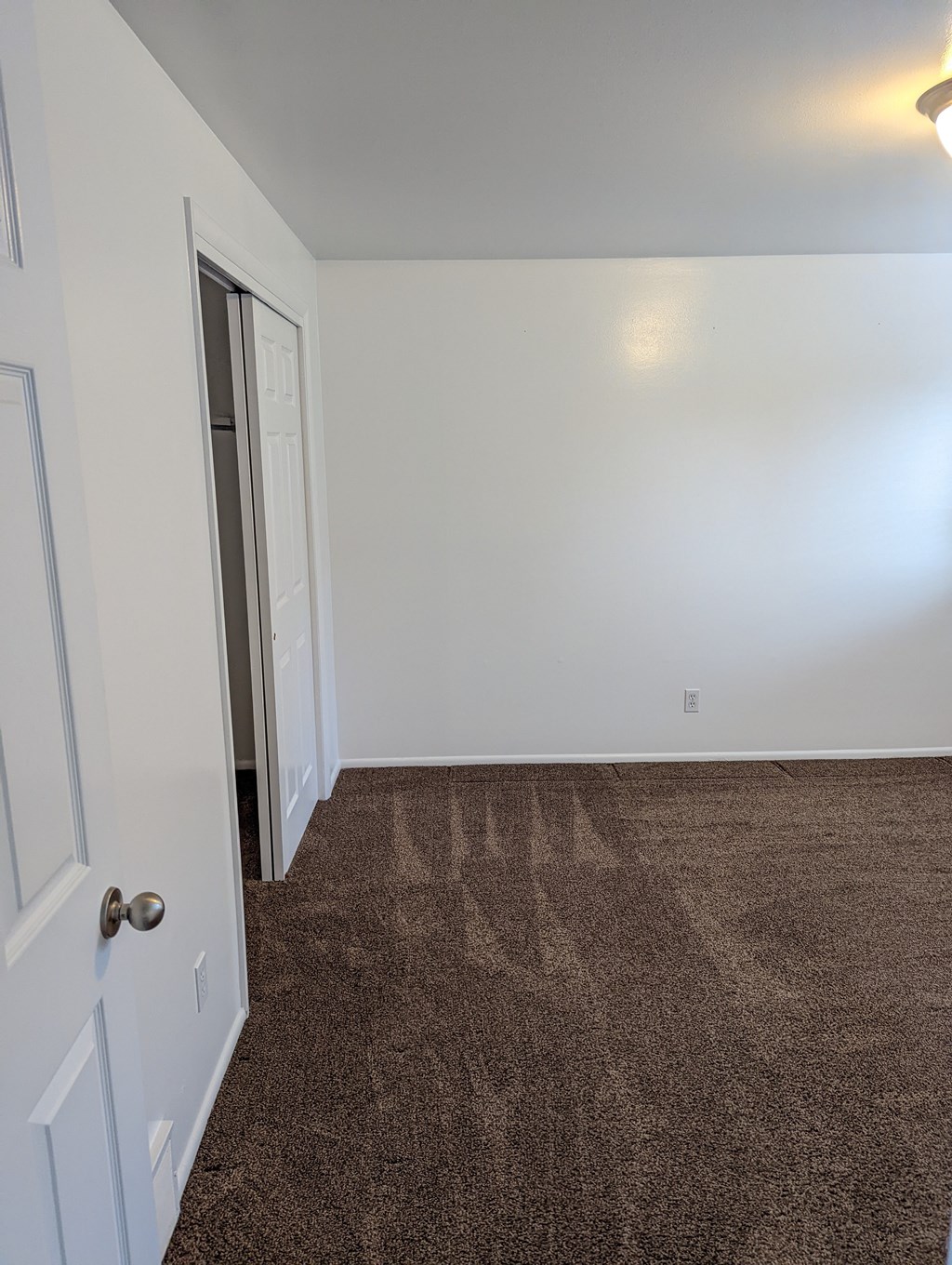 A room with a brown carpet and white walls.