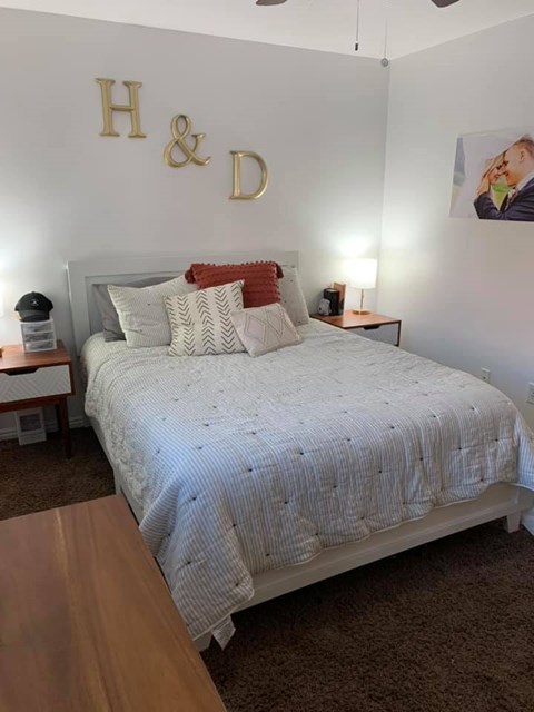 A bedroom with a bed, nightstands, and a ceiling fan.