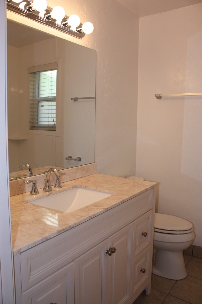 A white bathroom with a sink, toilet and mirror.