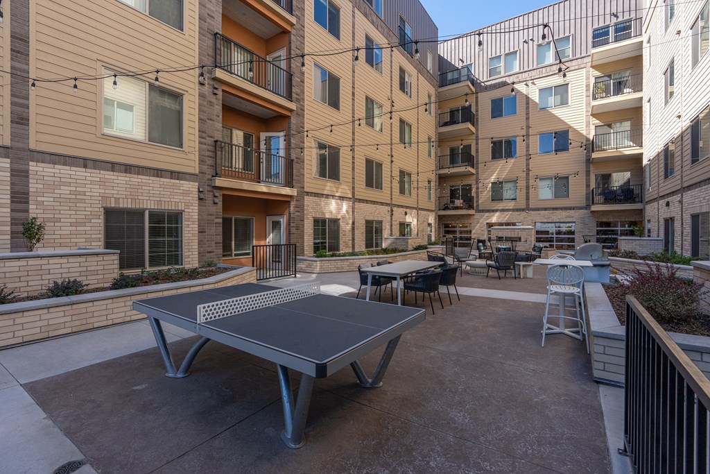 a patio with a ping pong table in front of an apartment building at The Revival, Salt Lake City, UT