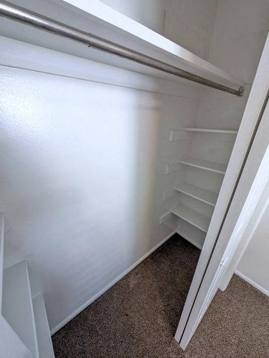 A white refrigerator with a metal handle and a white carpeted floor.