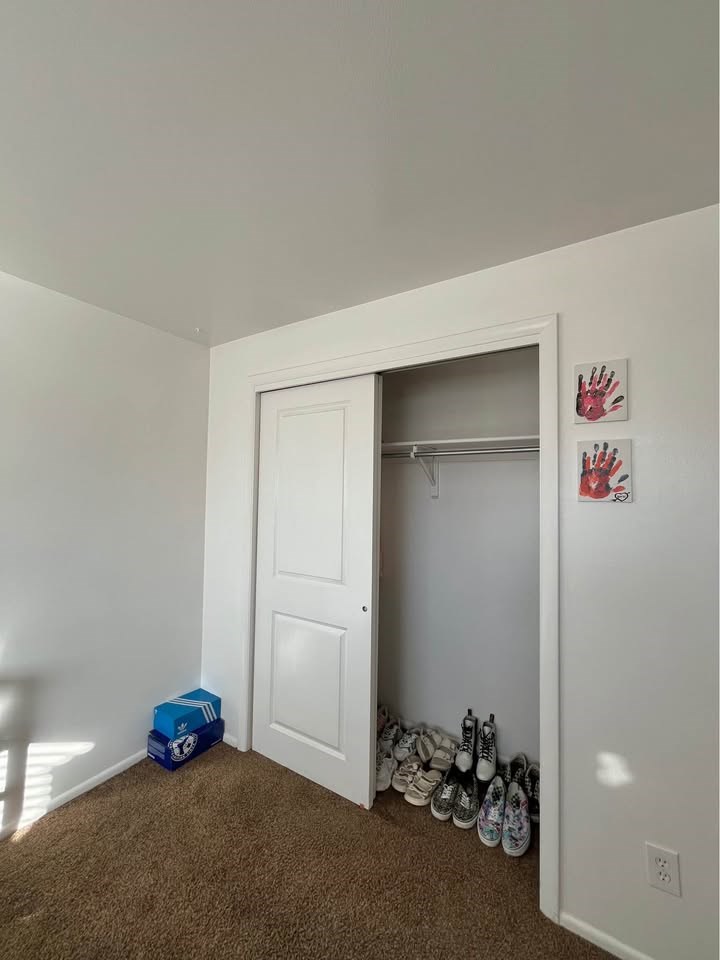 A white door is open to a hallway with a pair of shoes on the floor.