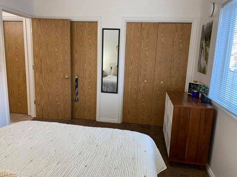 A bedroom with a bed, wardrobe, and a dresser.