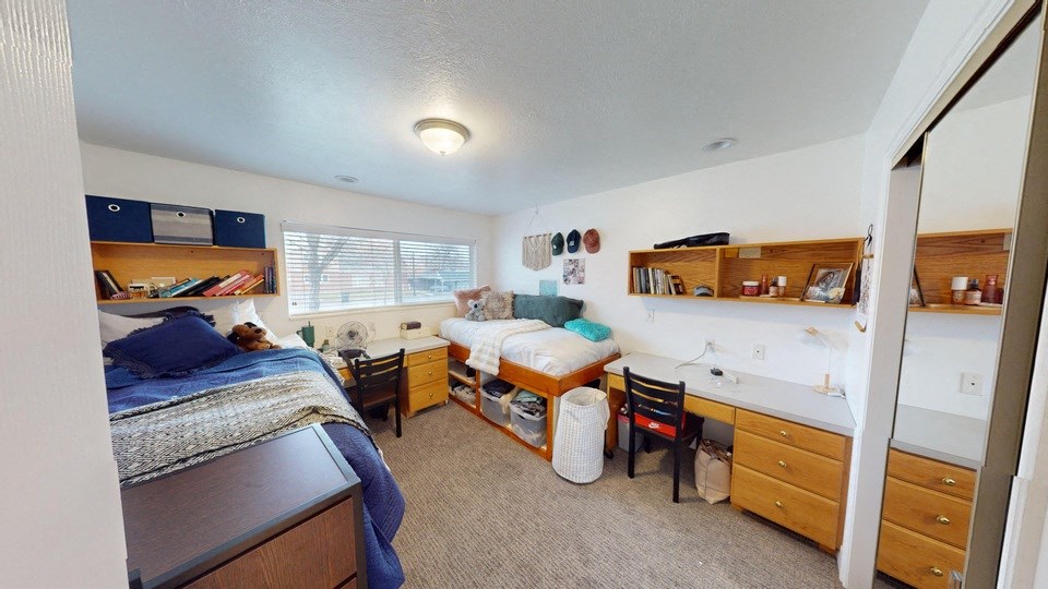 A bedroom with two beds and a desk.