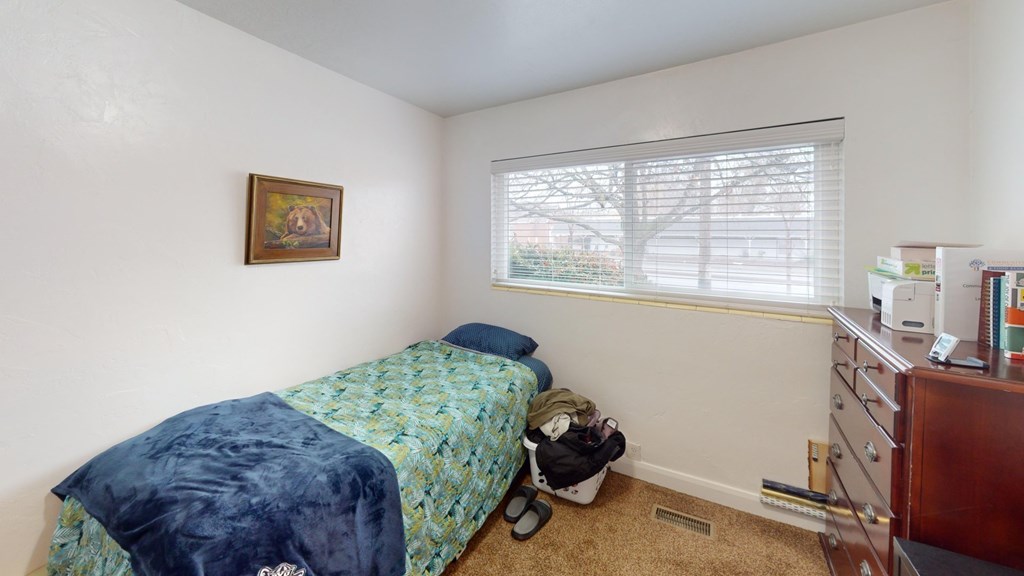 A bedroom with a bed, dresser, and window.