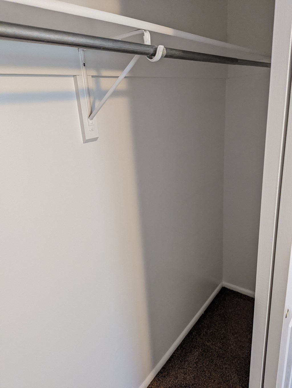 A white closet with a rod hanging from the ceiling.
