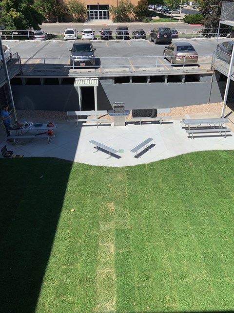 A parking lot with cars and a person with a stroller.