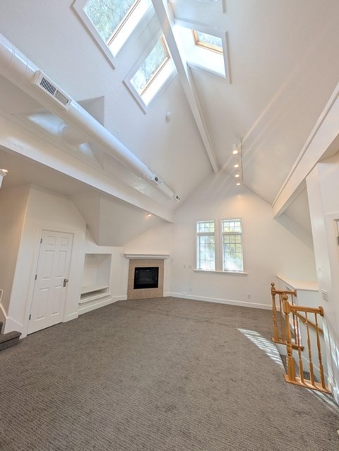 A spacious room with a fireplace and skylights.