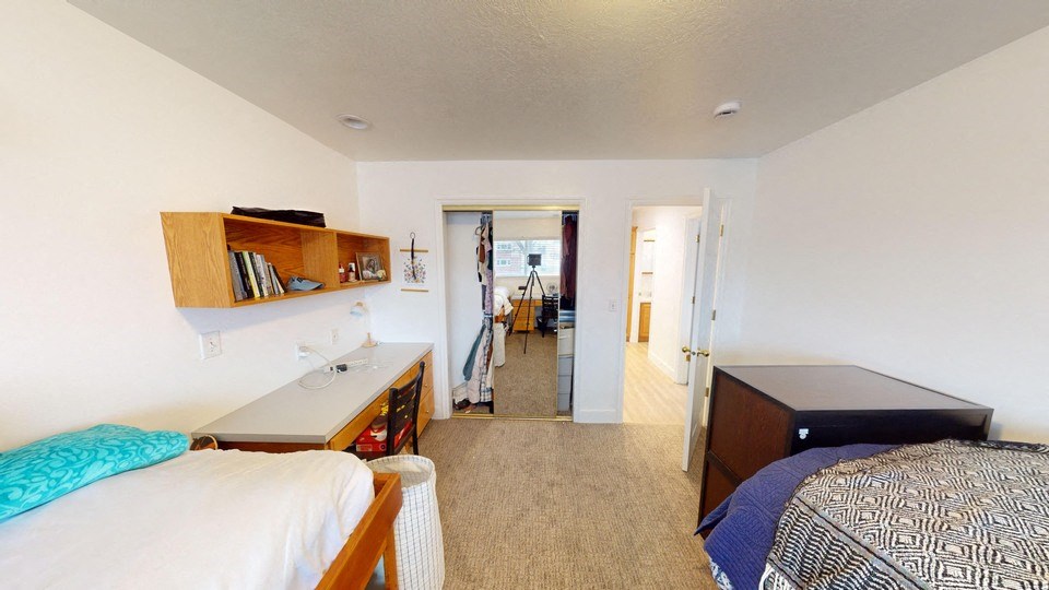 A bedroom with two beds and a desk.