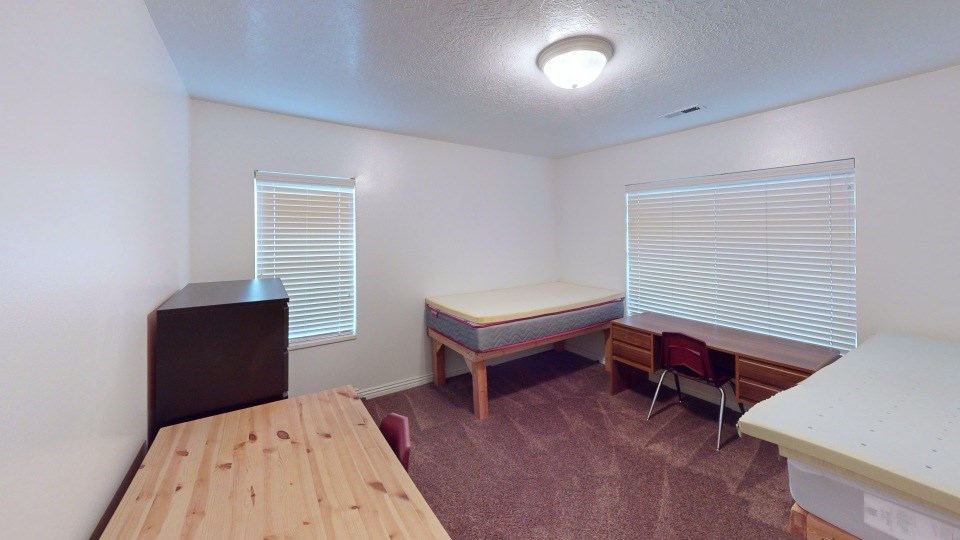 A room with a bed, a table, and a chair.