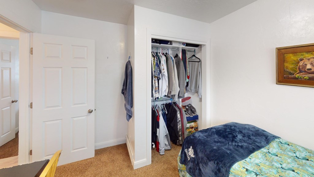 A bedroom with a bed, a wardrobe, and a painting on the wall.
