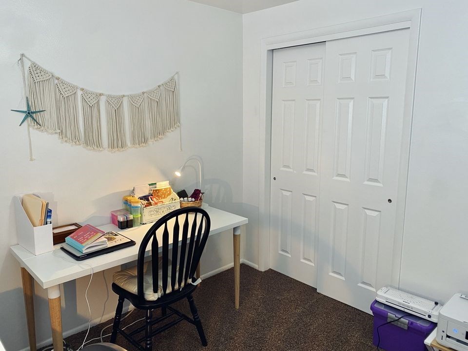 A white desk with a chair and a star decoration on the wall.