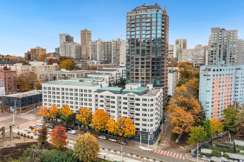 A cityscape with a mix of modern and older buildings, with trees showing autumn colors.