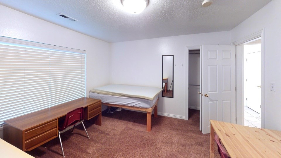 A bedroom with a bed, desk, and chair.
