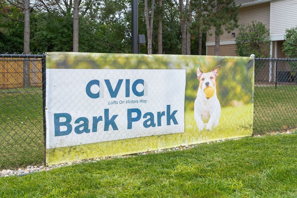 a sign that says bark park with a dog holding a tennis ball in its mouth