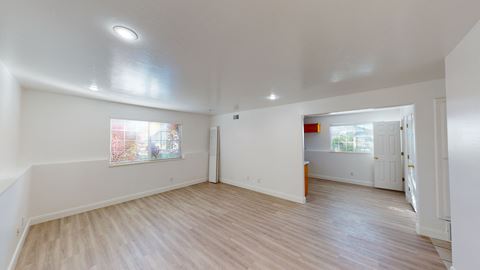 the living room and dining room of an empty house with white walls and wood floors