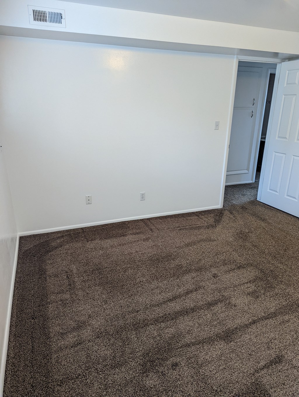 A room with a carpeted floor and a white door.
