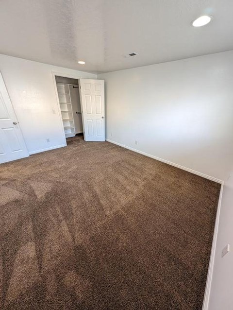 A room with a carpeted floor and a doorway leading to another room.