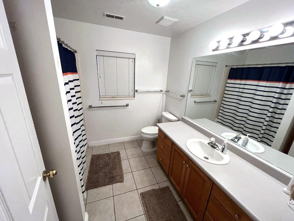 A bathroom with a toilet, sink, and mirror.