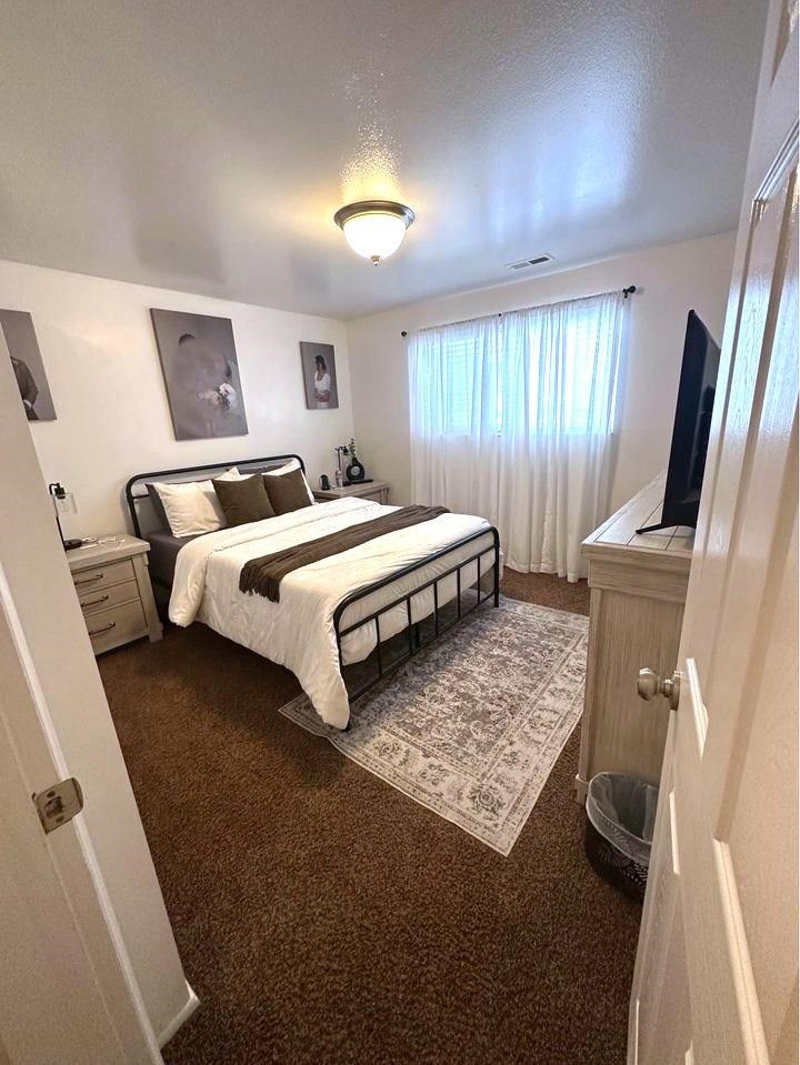 A bedroom with a bed, nightstand, and two pictures on the wall.