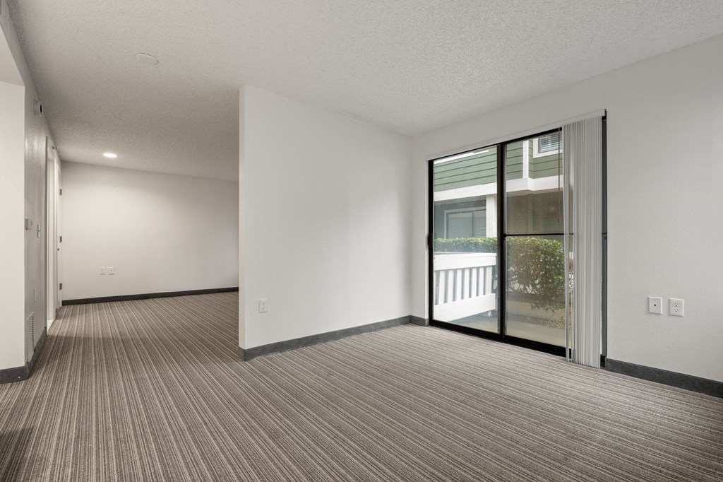 A room with a carpeted floor and a sliding glass door. at AVIA Lofts on Parkway Apartments, Vancouver, WA