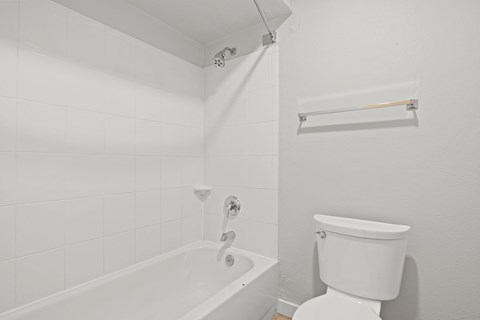 a white bathroom with a tub and a toilet at AVIA Lofts on Liberty Ridge Apartments, Jacksonville, FL, 32256