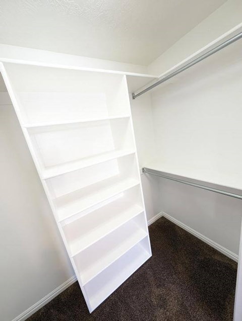 A white shelving unit in a corner of a room.
