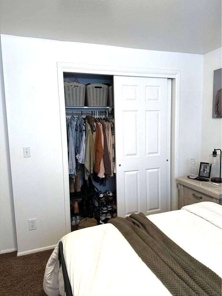 A white bedroom with a bed, a wardrobe, and a nightstand.