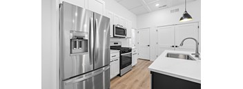 A modern kitchen with a stainless steel refrigerator and white cabinets.at Alante Homes at Spring Run, Caldwell, ID