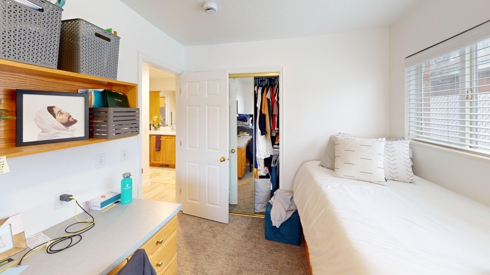 A bedroom with a bed, a desk, and a closet.